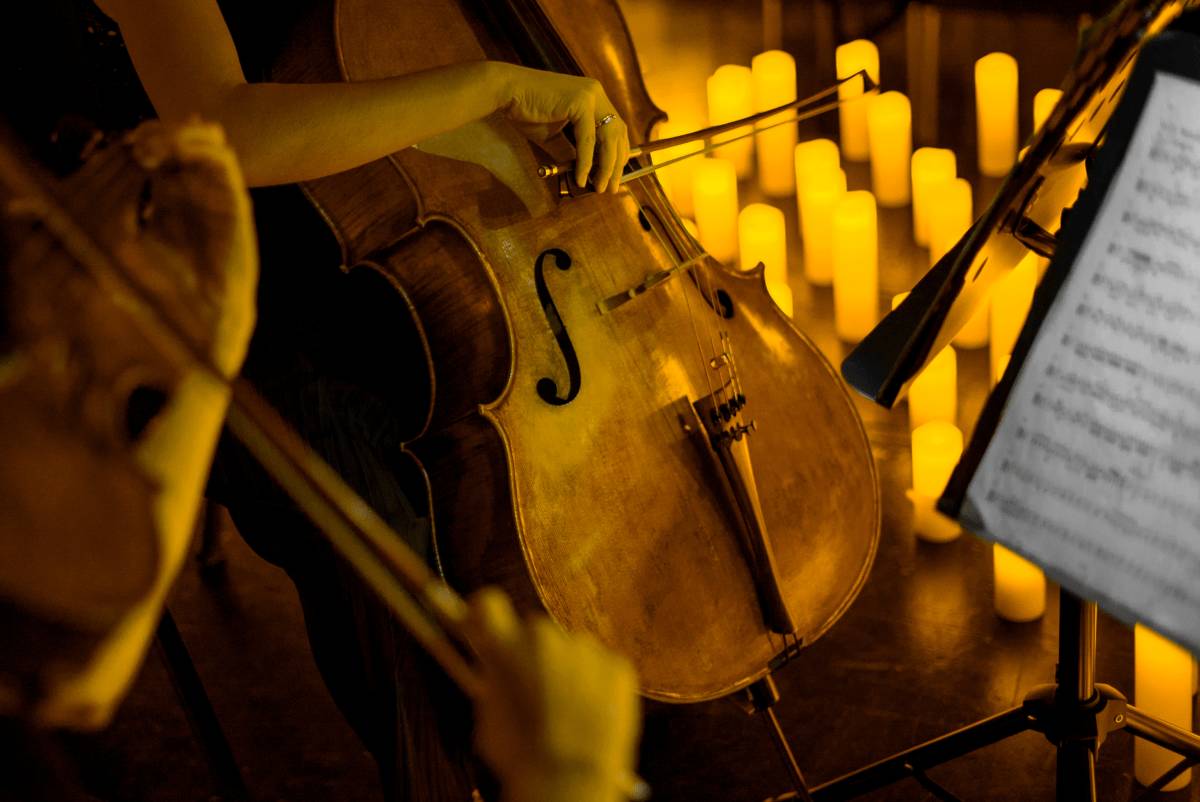 Un'inquadratura ingrandita di un violoncellista che suona al lume di candela.
